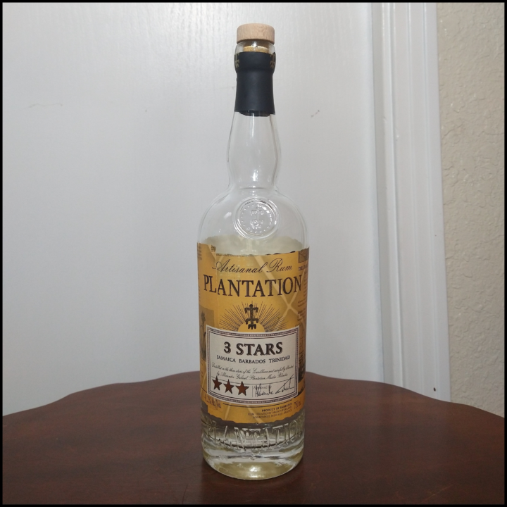 Bottle of Plantation 3 Star Rum sitting on a dark brown table in front of a white door