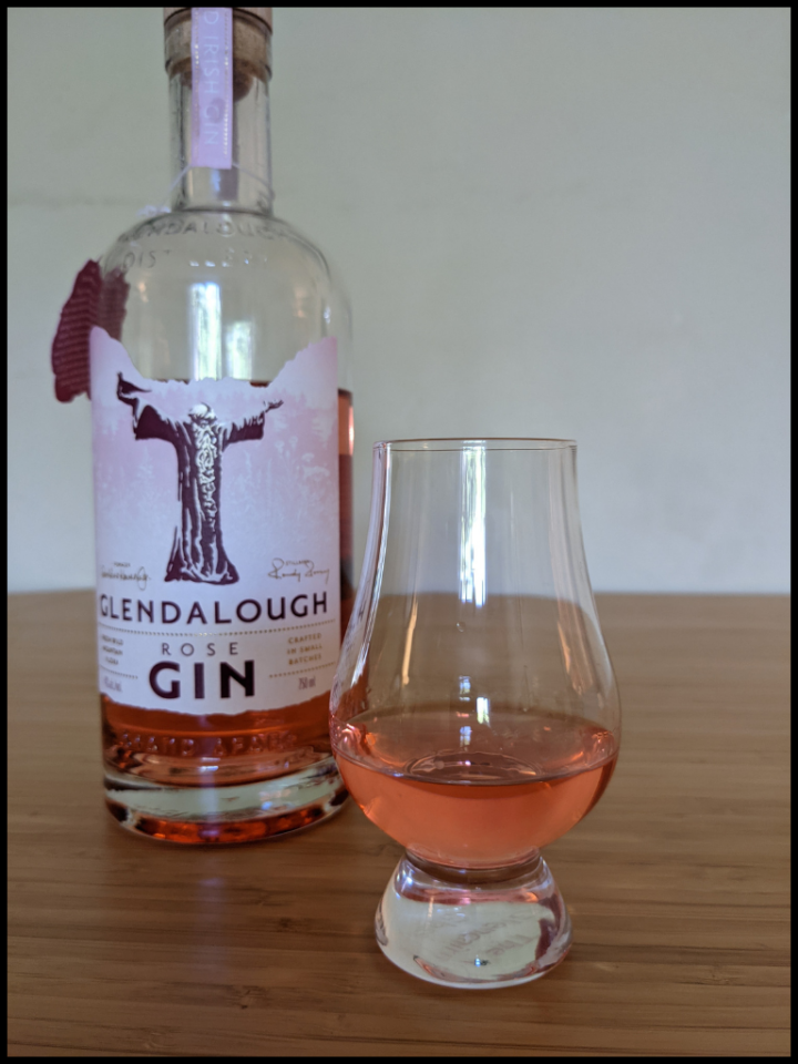 Pink liquid in a glencairn glass with the Glendalough Rose Gin bottle in the background