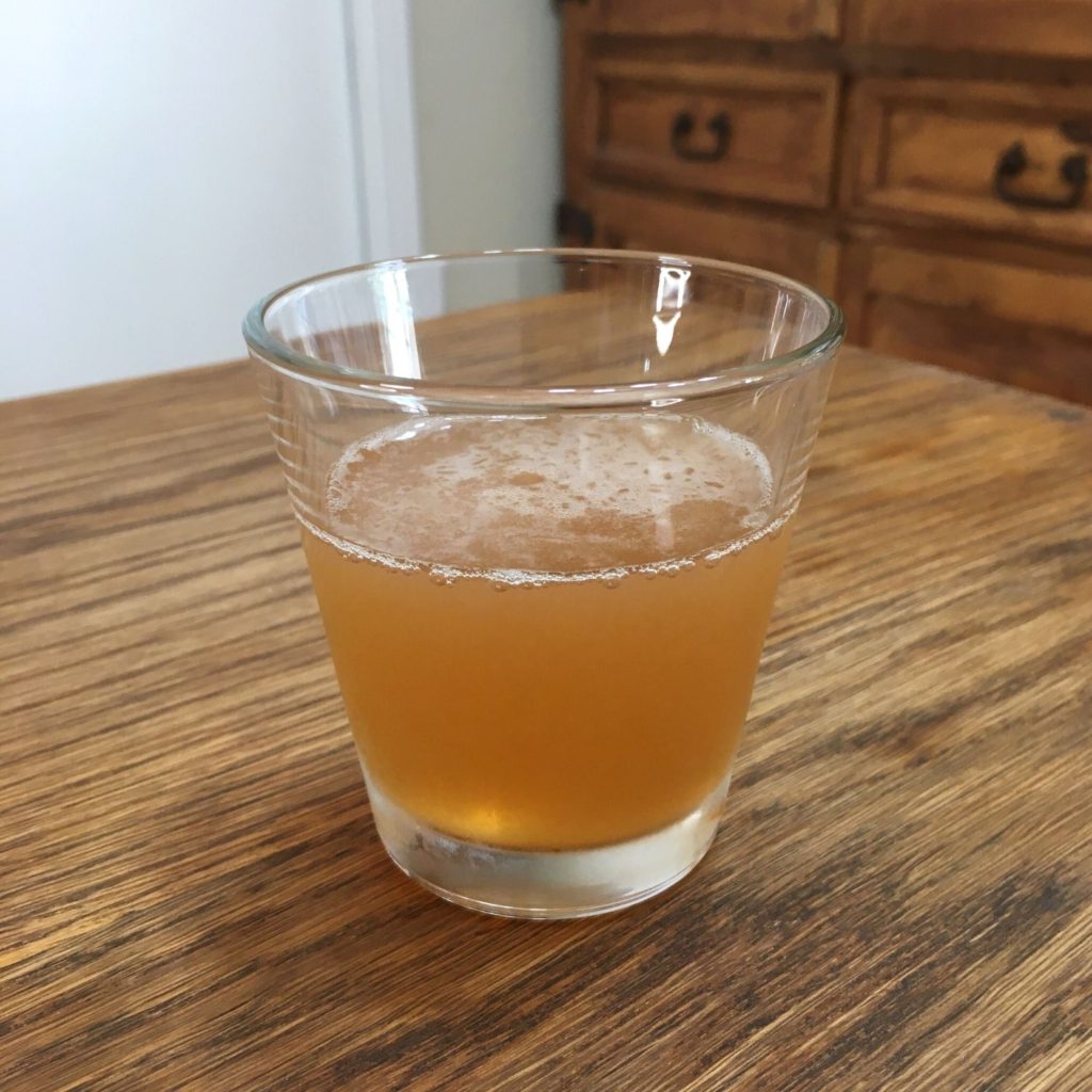 deep golden cocktail with slight foaming, sitting on a wooden table