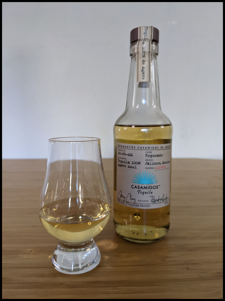 gold liquid in a glencairn glass with a liquor bottle in the background