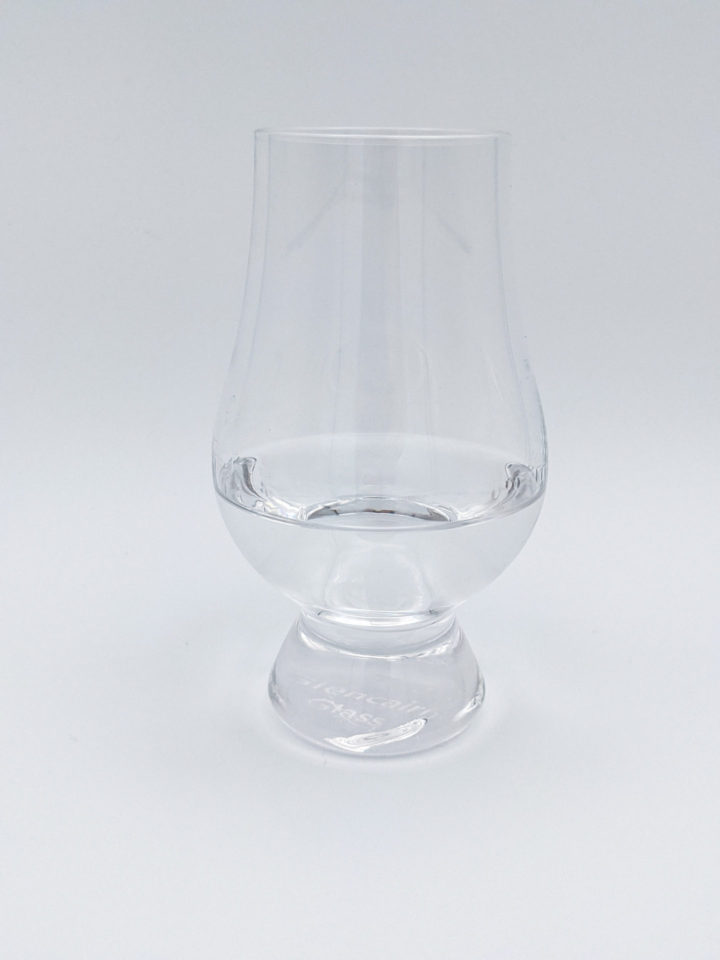 Clear liquid in a glencarin glass with a white background