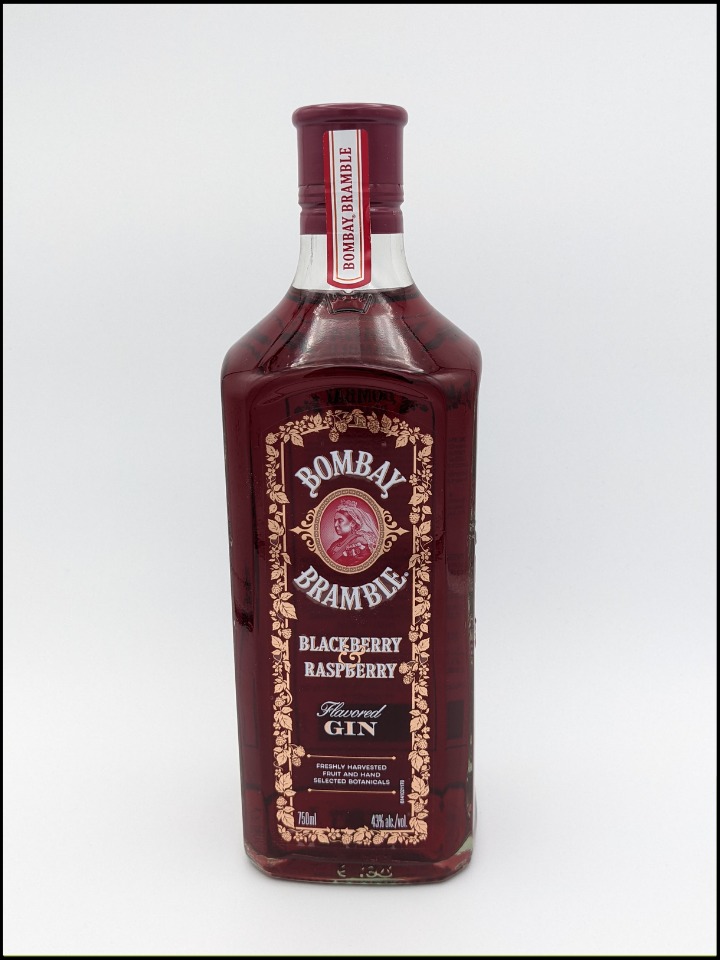 tall clear bottle with dark red liquid with white lettering and ornate gold decoration around the label