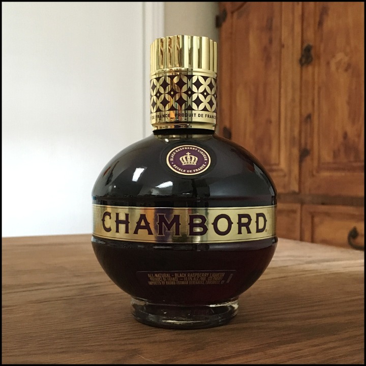 Rounded bottle of Chambord Black Raspberry Liqueur sitting on a wooden table