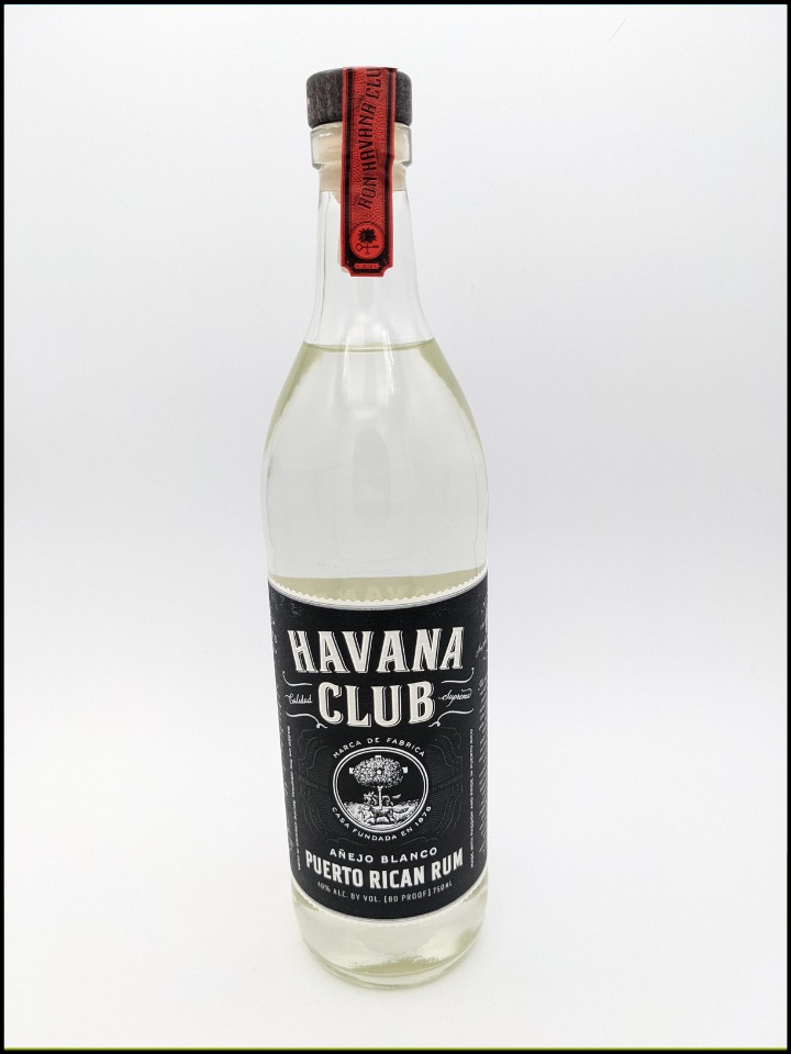 Tall glass bottle full of clear liquid with a black label and white lettering