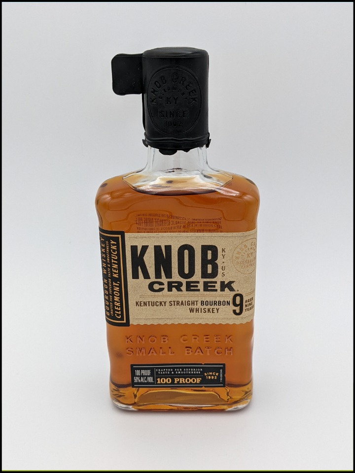 rectangular shaped bottle with large black wax top. light brown label with black lettering