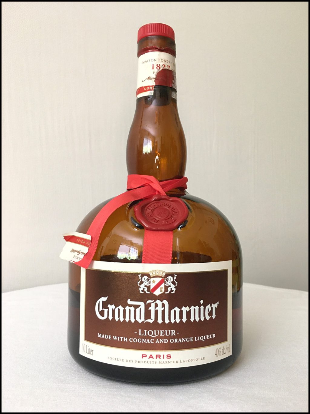 Bottle of Grand Marnier Cordon Rouge sitting on a white tablecloth, in front of a white background