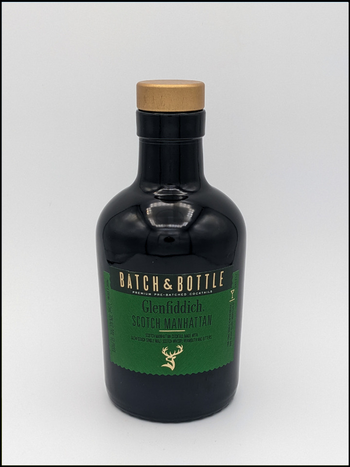 Black glass bottle with a gold top and green label