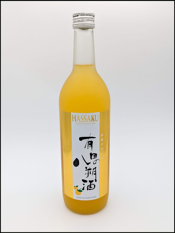 Tall glass bottle filled with orange liquid and a label with the Hassaku Sake branding