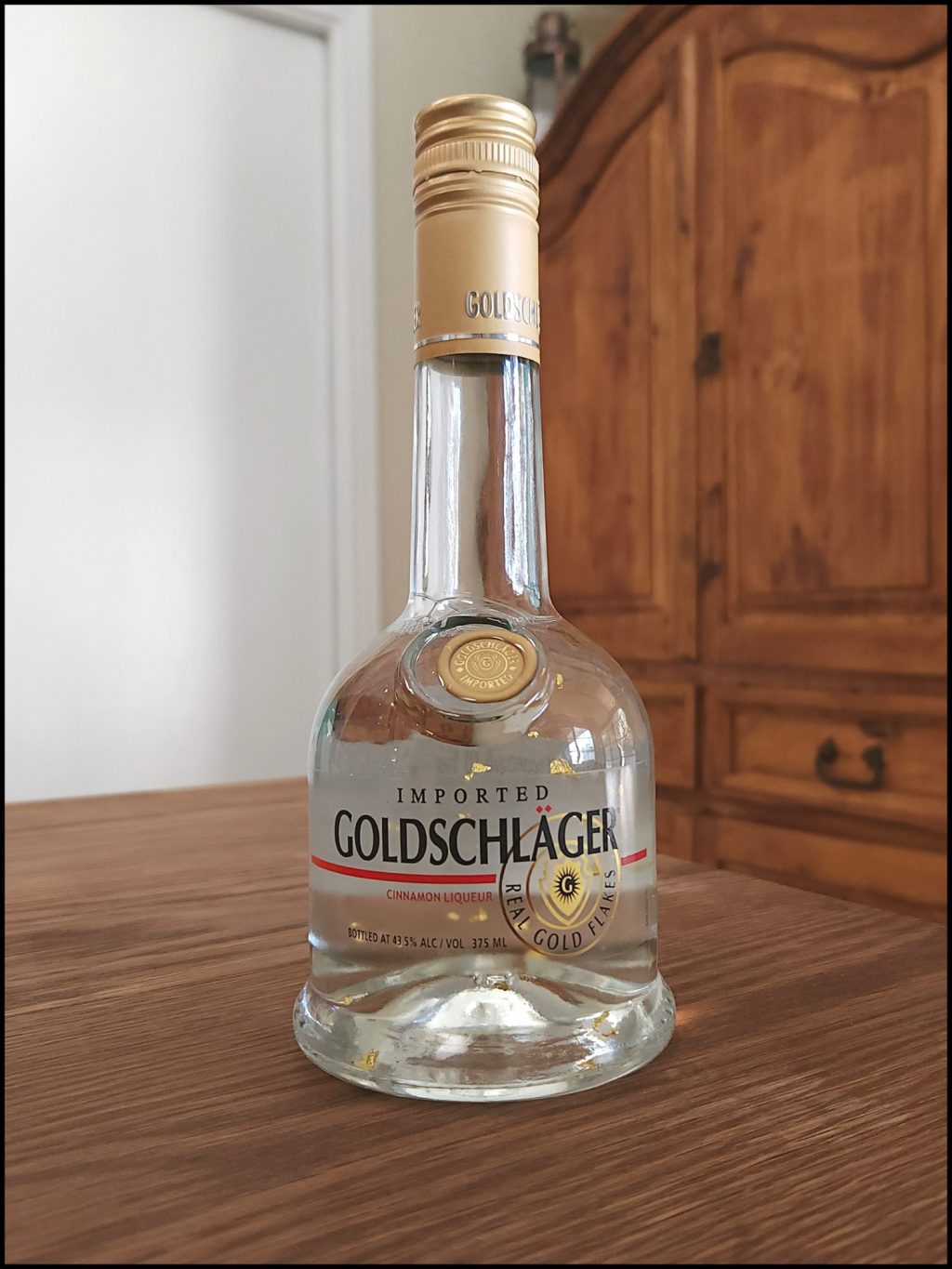 Bottle of Goldschläger Cinnamon Schnapps sitting on a wooden table