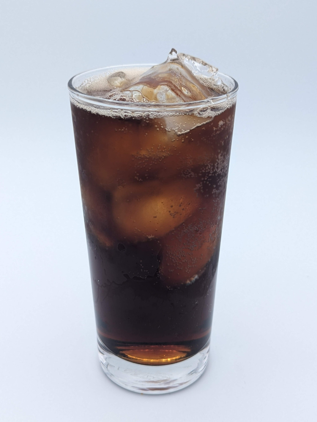 dark brown liquid in a tall glass filled with ice