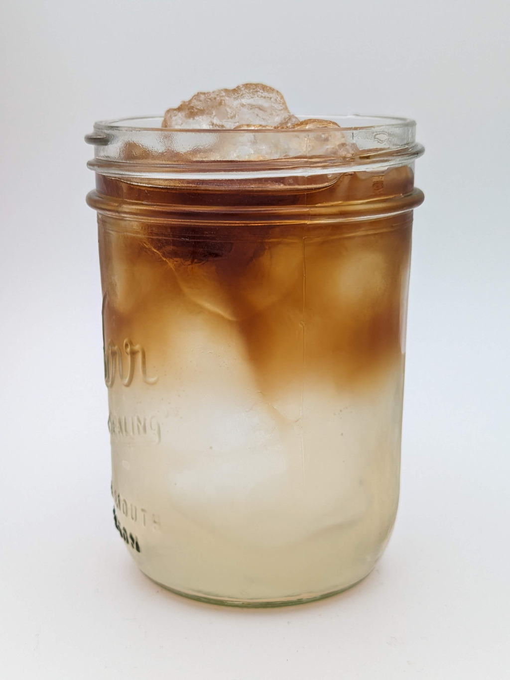 light cream colored liquid with a dark brown rum float in a glass jar