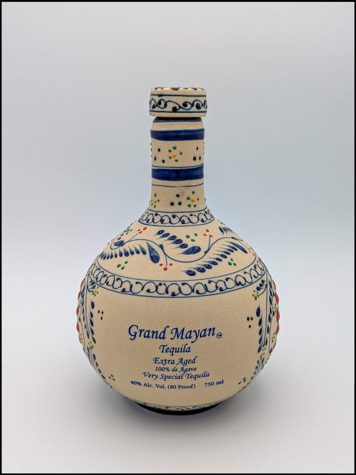 round ceramic bottle with blue lettering that reads Grand Mayan Extra Aged and hand painted flower design