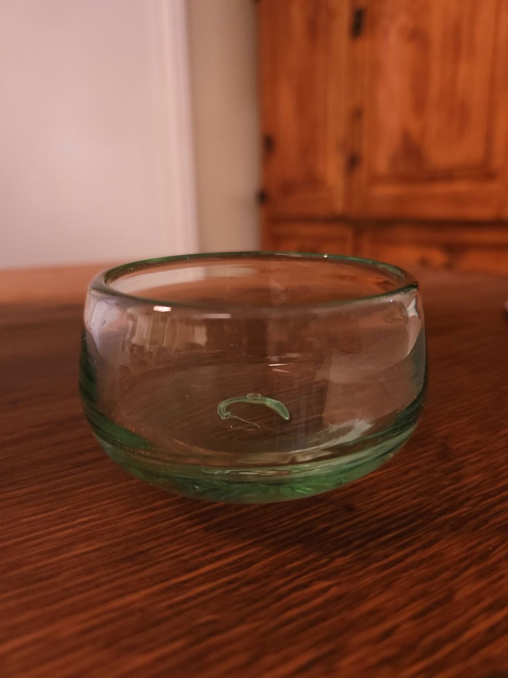 clear glass copita partway filled with clear liquid, sitting on a wooden table