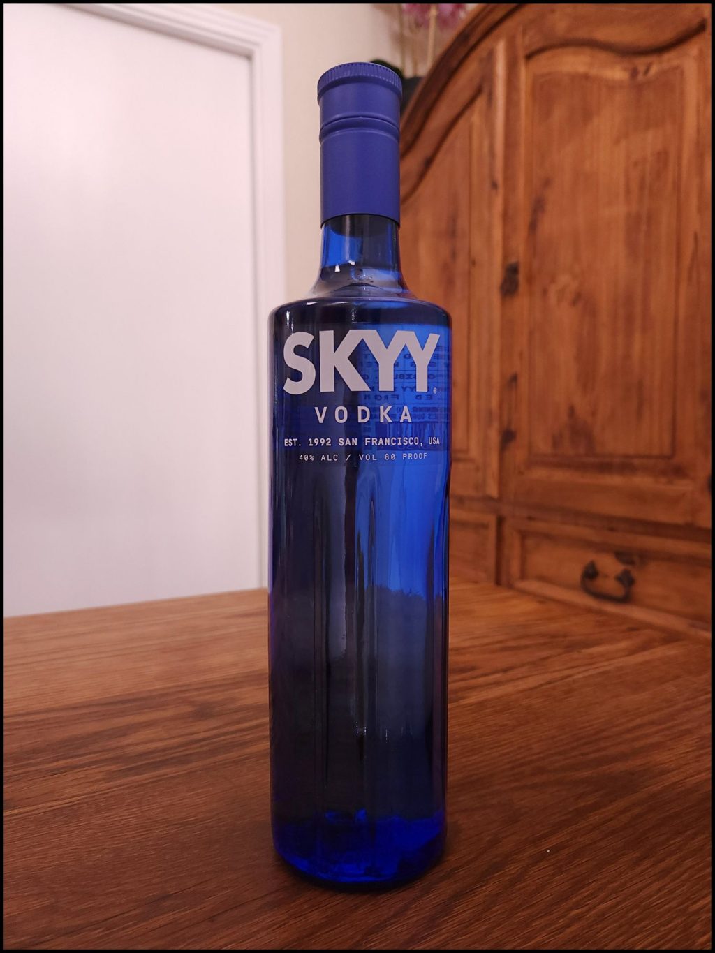Bottle of Skyy Vodka with cobalt blue glass and white lettering, sitting on a wooden table